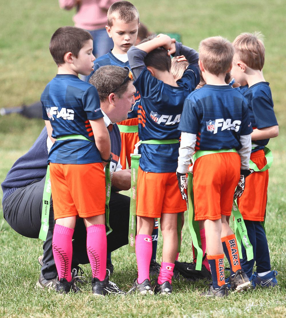 A team in orange shorts huddles together before the snap