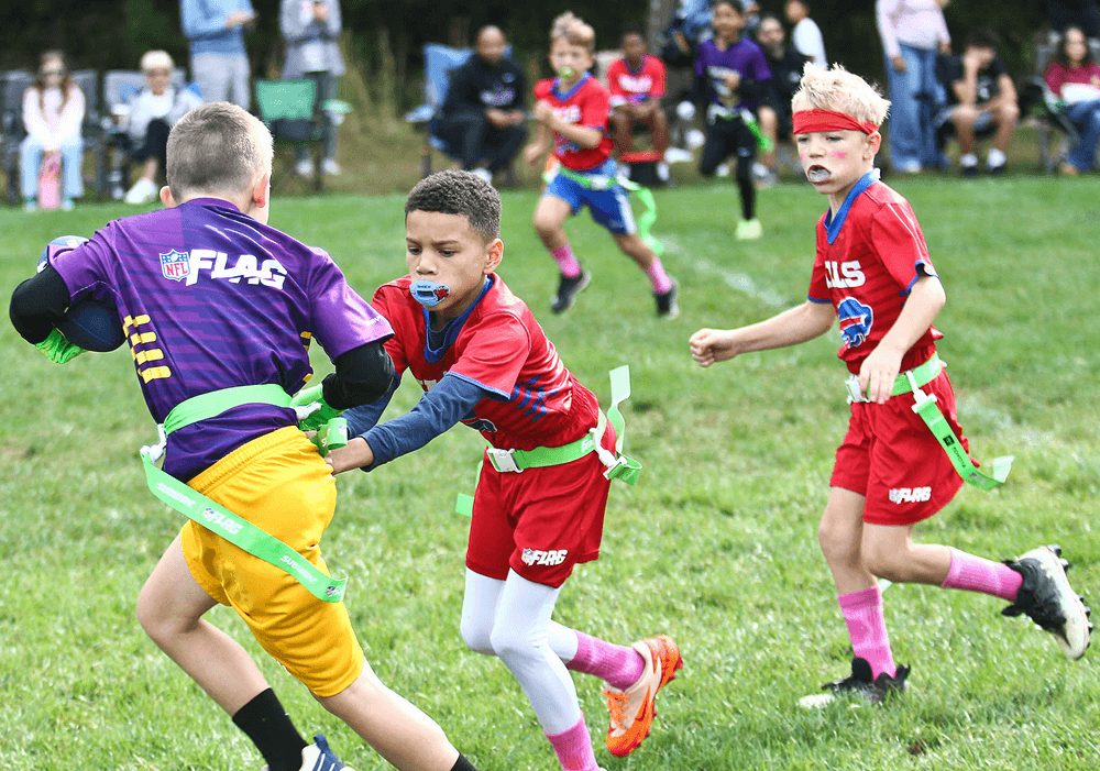 A ball carrier in purple runs as defenders in red close in