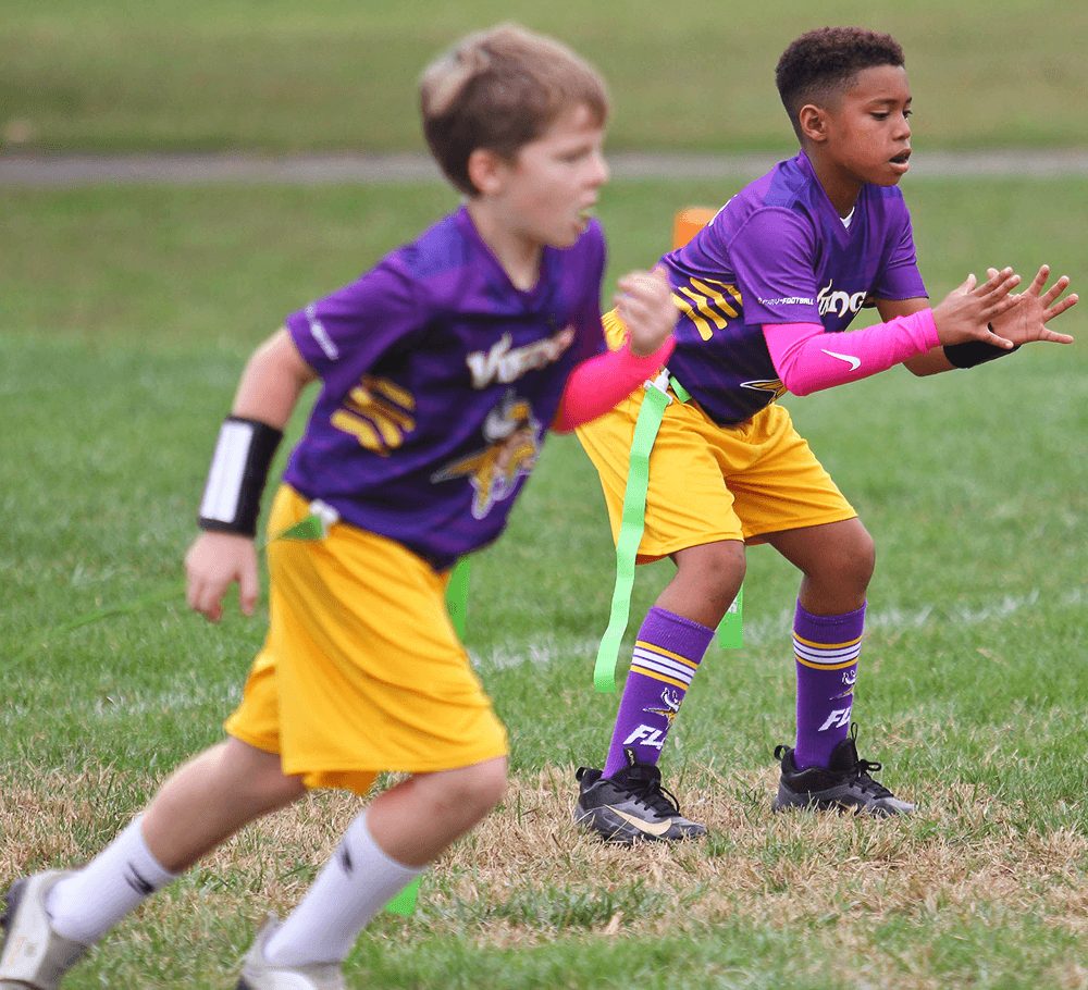 Players in purple and yellow converge on the ball carrier