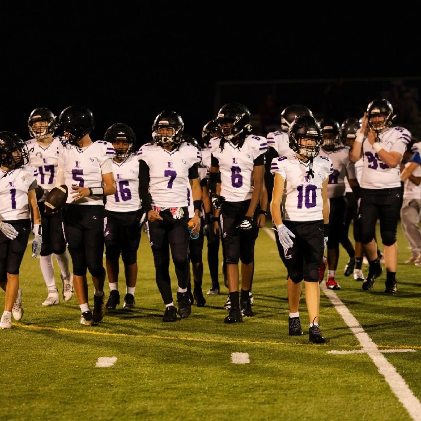 Aim High Panthers tackle players walk onto the field in helmets for a night game